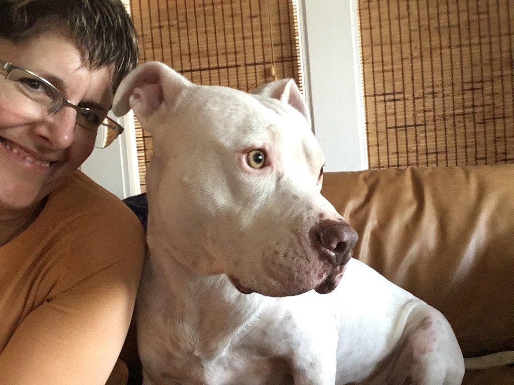 Virginia relaxing on a couch with a white dog beside her