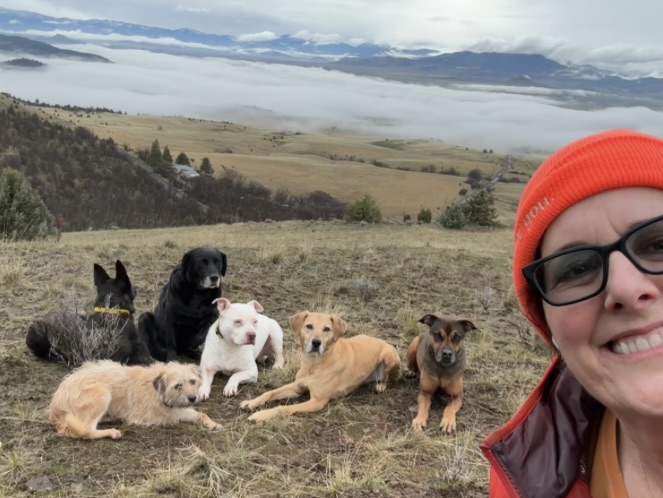 Virginia with a group of dogs on a hillside overlooking the expansive Montague landscape