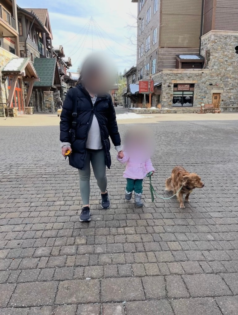 Frankie walking through a mountain village with her human sister and mother, whose faces are blurred for privacy